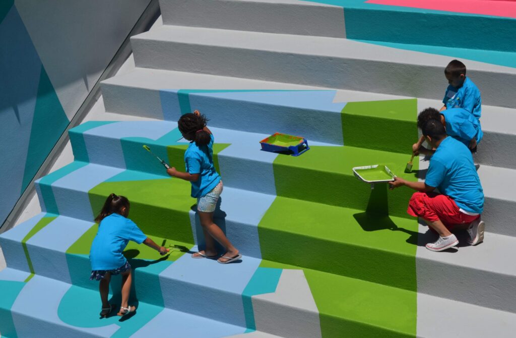 Children paint steps to their school with bright colors
